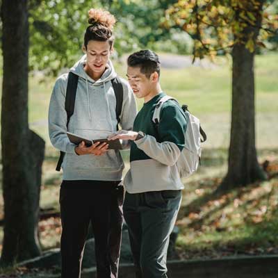 two students looking at a notebook together in a park