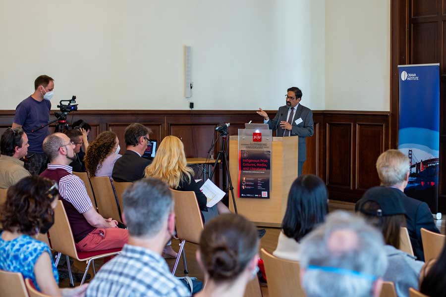 A speaker standing behind a podium addressing a seated audience.