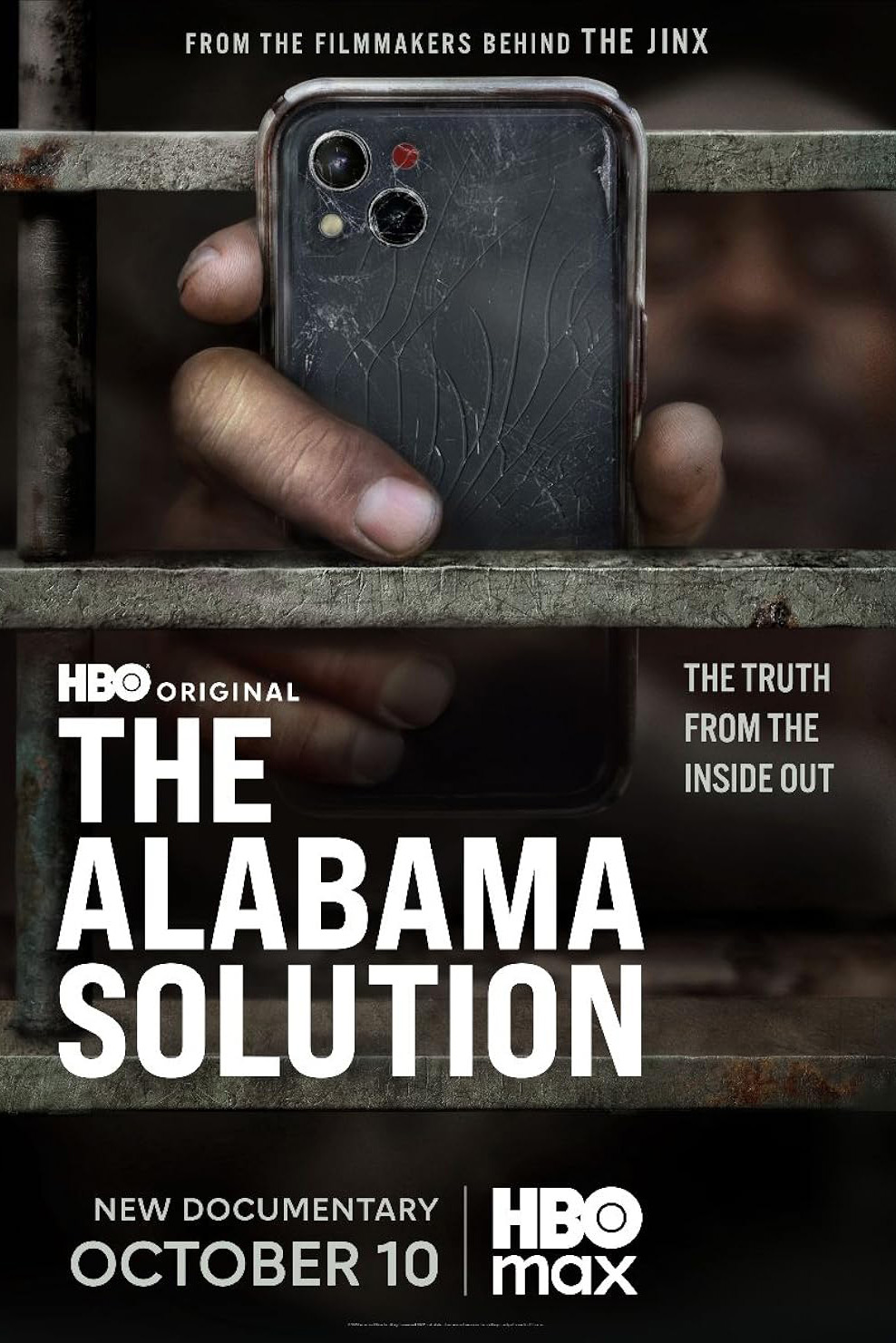 A movie poster for 'The Alabama Solution' including the fim title and a photo of a hand holding a cracked cellphone through metal bars