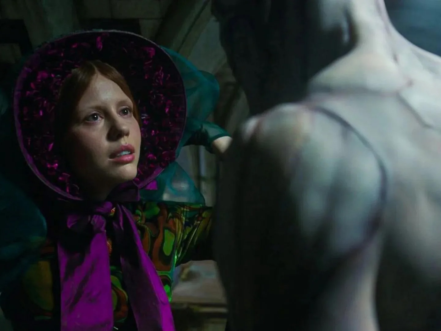 A woman in 19th Century dress looks up towards Frankenstein's monster